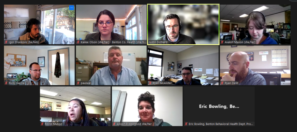 A screencap of a virtual meeting featuring various professionals talking, smiling, and listening.