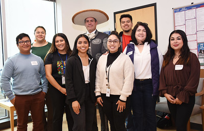 A group of Latinx people stand with a person wearing traditional Mexican vaquero celebration attire.