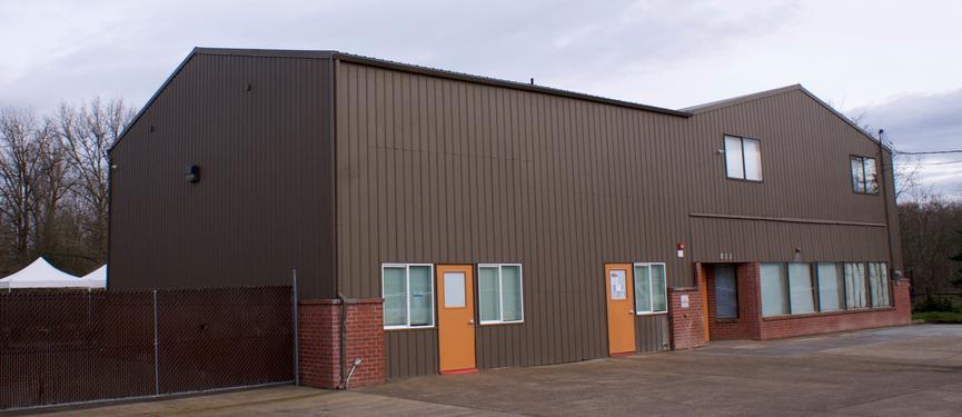 A large brown warehouse-style building with red brick accents and orange doors.