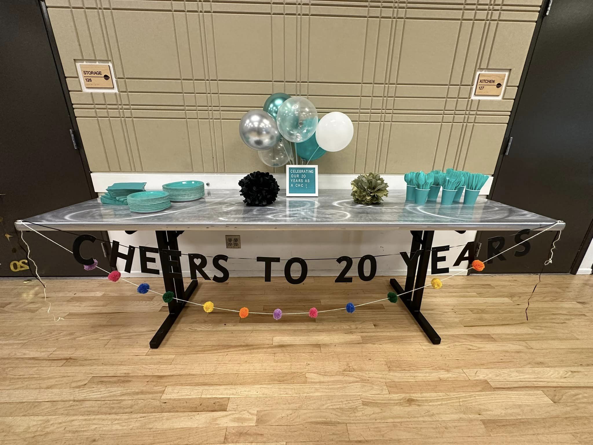 A party banner with teal colored plates, cups, and decor.