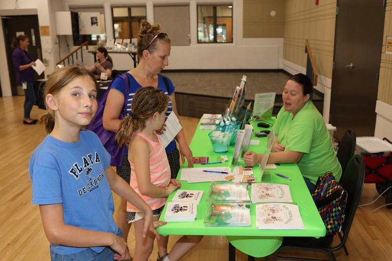 A family visits a resource booth decked out in bright green colors.