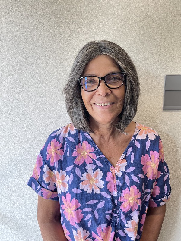 A woman with shoulder-length hair wearing a floral top.