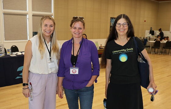 Three people pose together and smile for a photo.