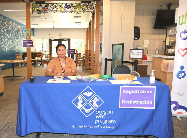 A person behind a registration table with a blue tablecloth.