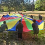 People playing games with a colorful playground parachute.