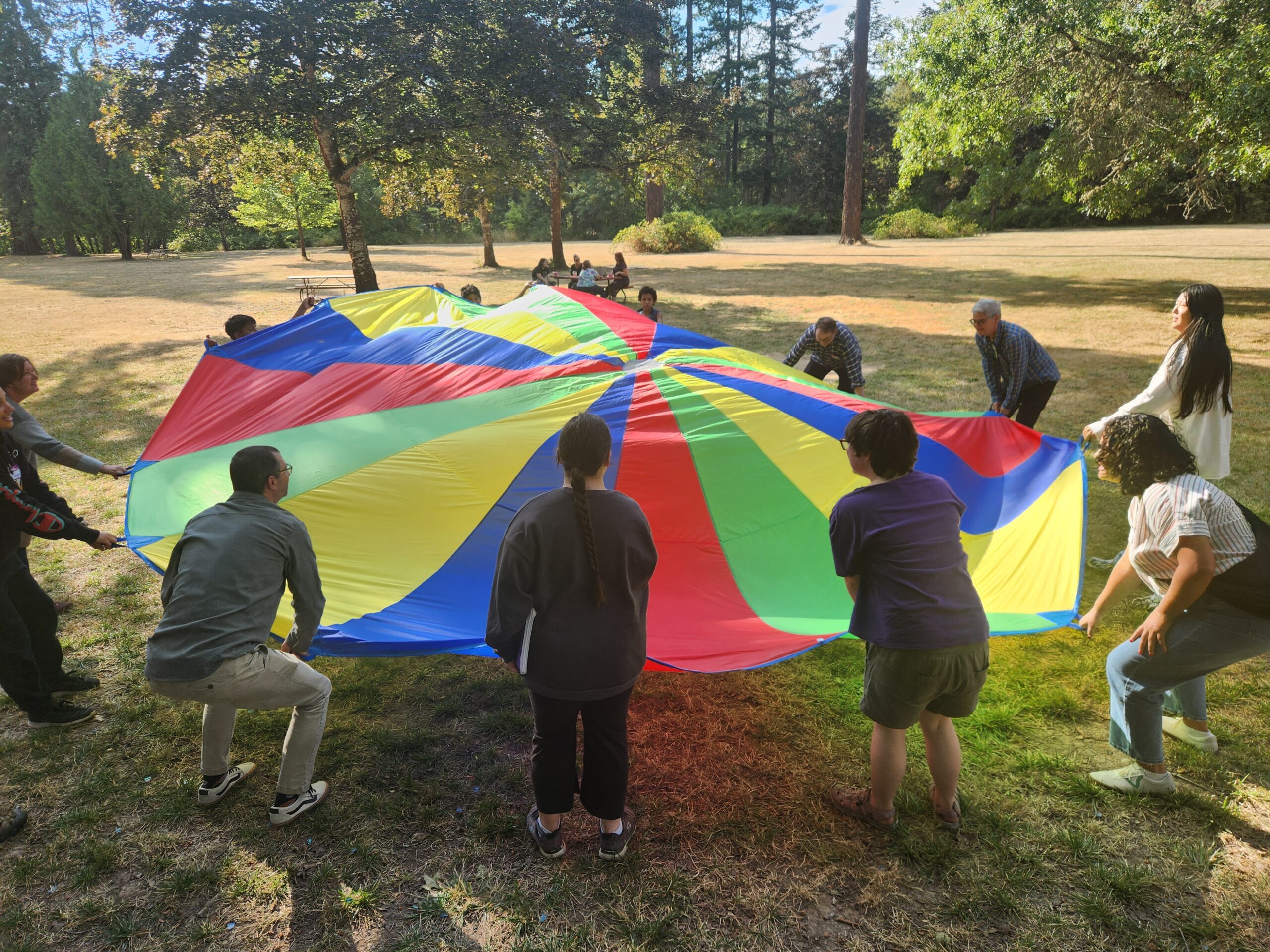 People playing games with a colorful playground parachute.