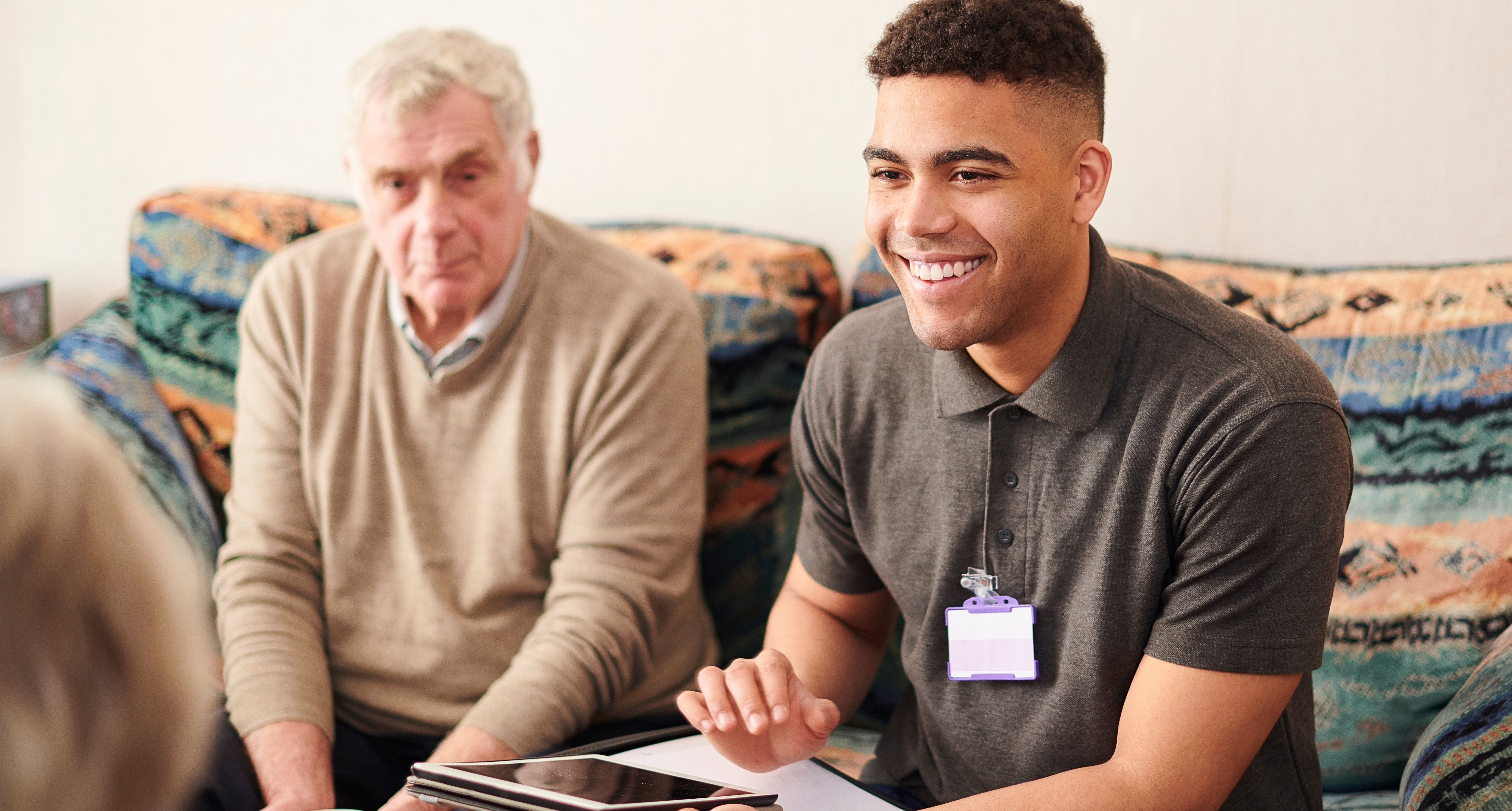 An adult male helps an elderly couple complete paperwork.