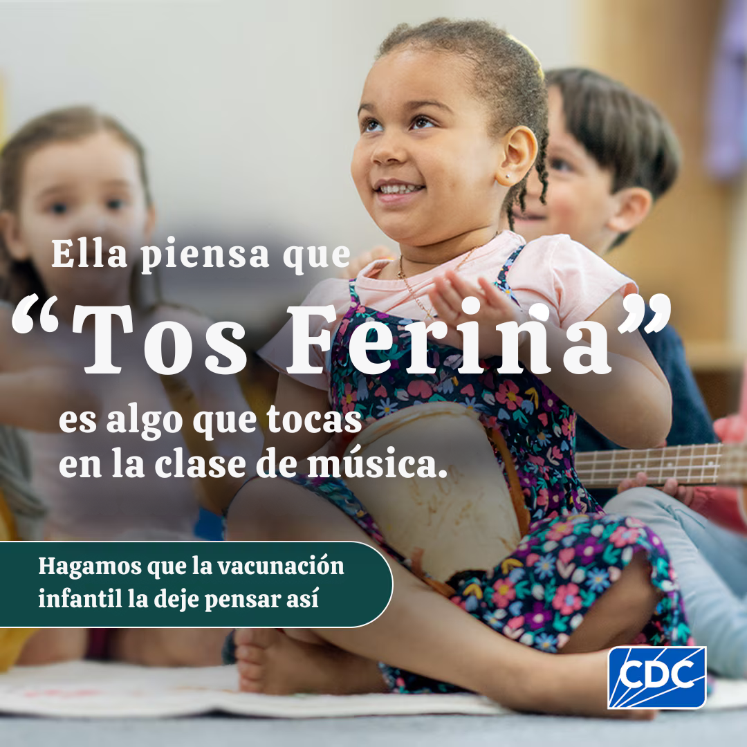 A young girl plays a drum in a classroom with other children.