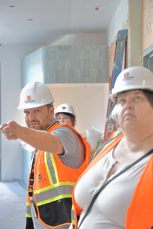 Benton County Crisis Center Project Manager, Ricky Garcia points out wall tiles and other design features in shades of light blues and greens that help present a calming and therapeutic atmosphere.