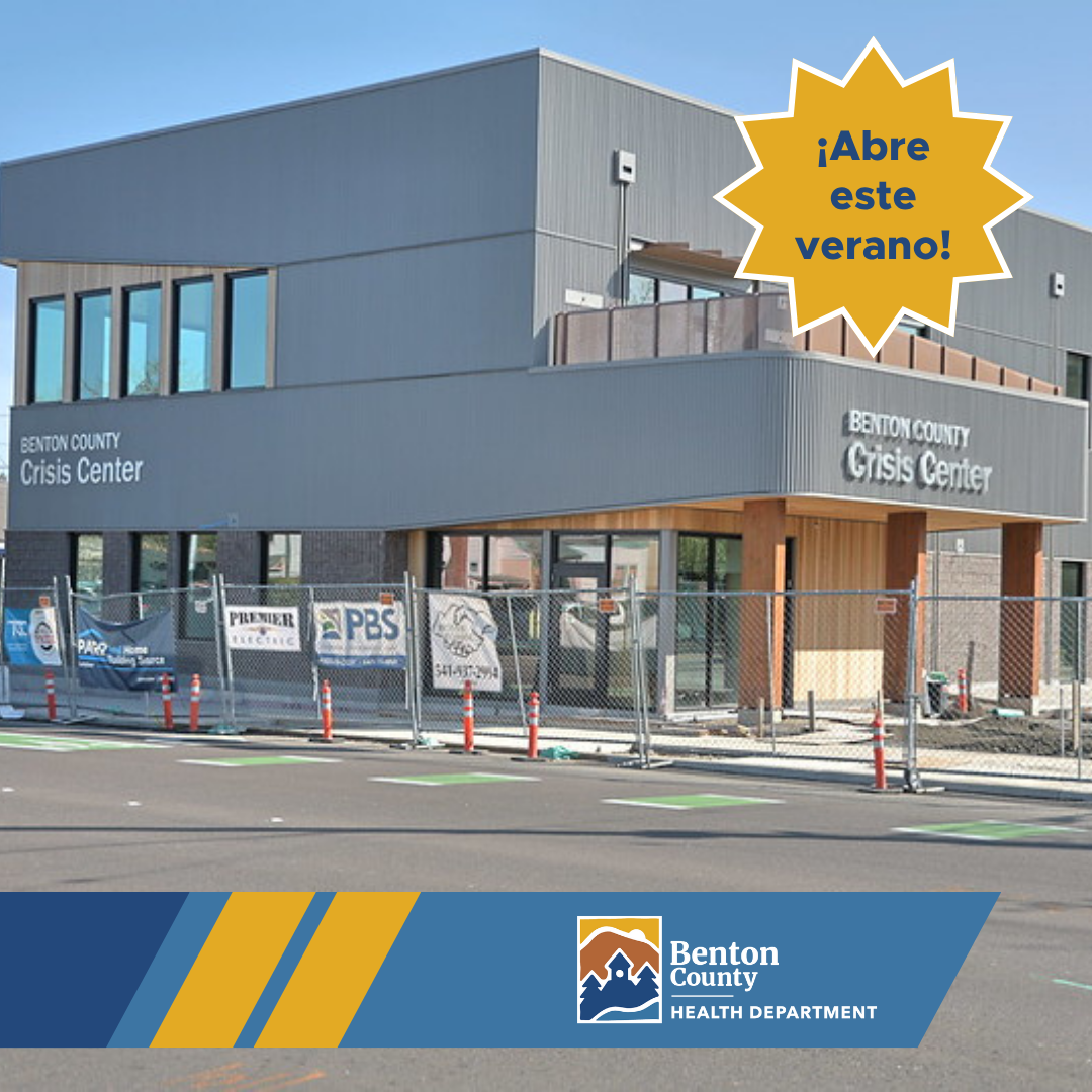 The Benton County Crisis Center building surrounded by a construction fence. A gold star outlined in white with dark blue text reads, "¡Abre este verano!"