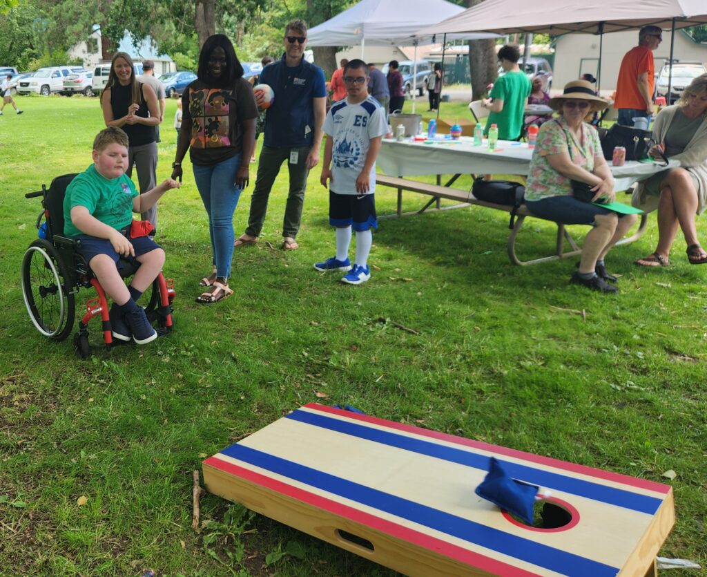 People enjoying playing a game of cornhole at a park.
