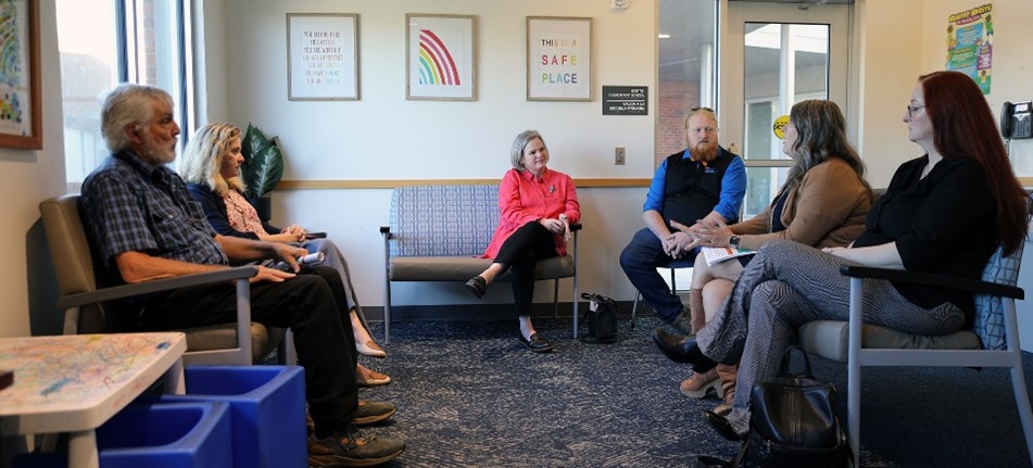 Six local and state leaders sitting in a clinic waiting room.