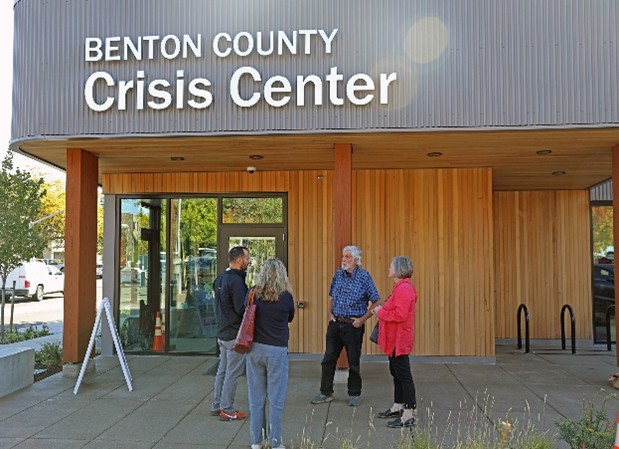 Benton County Crisis Center building with wooden siding and four individuals standing in front of the building.