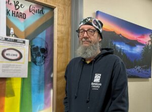 male standing in hallway with Crater Lake painting in the background and welcome sign.