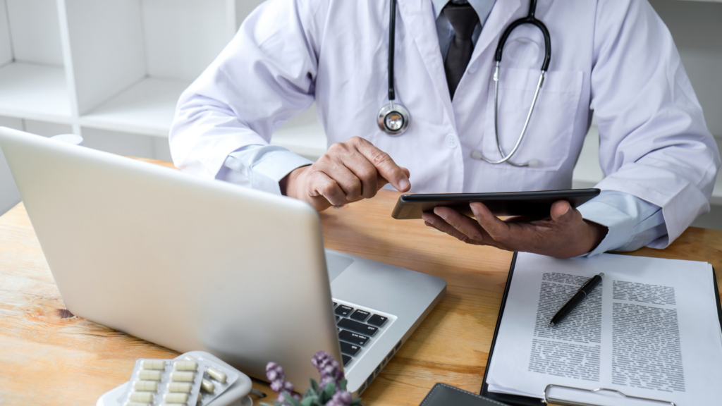 Doctor studying with a laptop, a tablet and paper documents