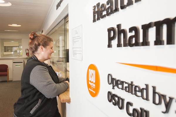A person stands at the window of the Health Services Pharmacy.