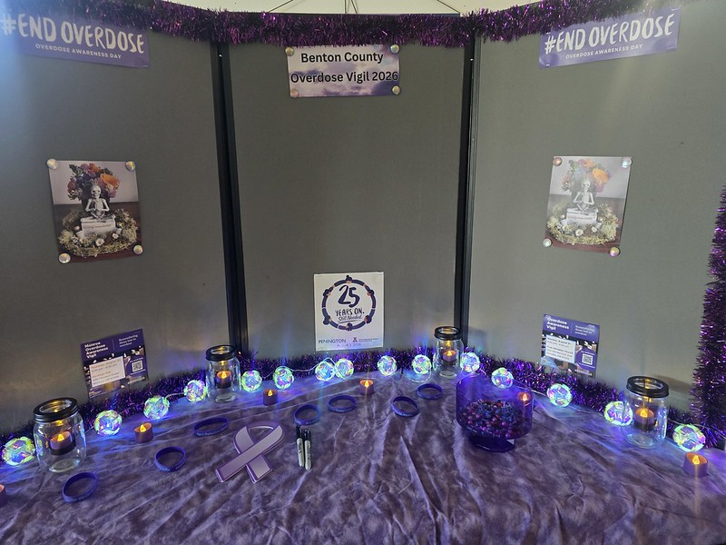 Memorial display for Benton County Overdose Vigil 2020 with purple lights, candles, and #ENDOVERDOSE signs on a gray backdrop.