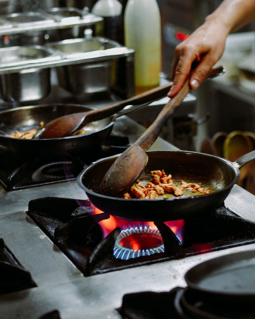 A person cooking over a flame in a restaurant kitchen