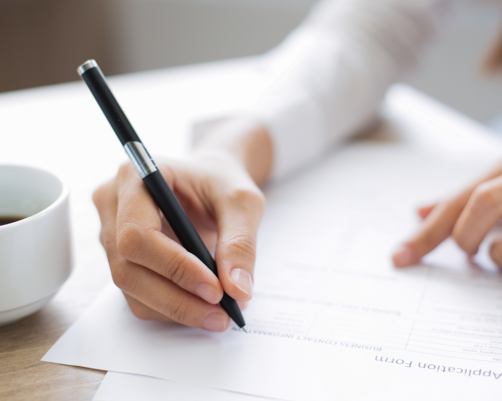 A hand filling out an application